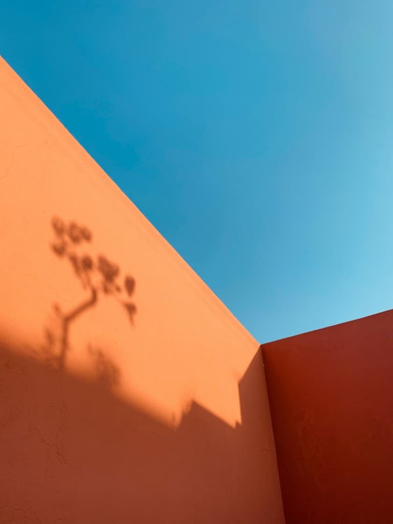 Terracotta architectural walls meeting at a corner beneath a clear blue sky
