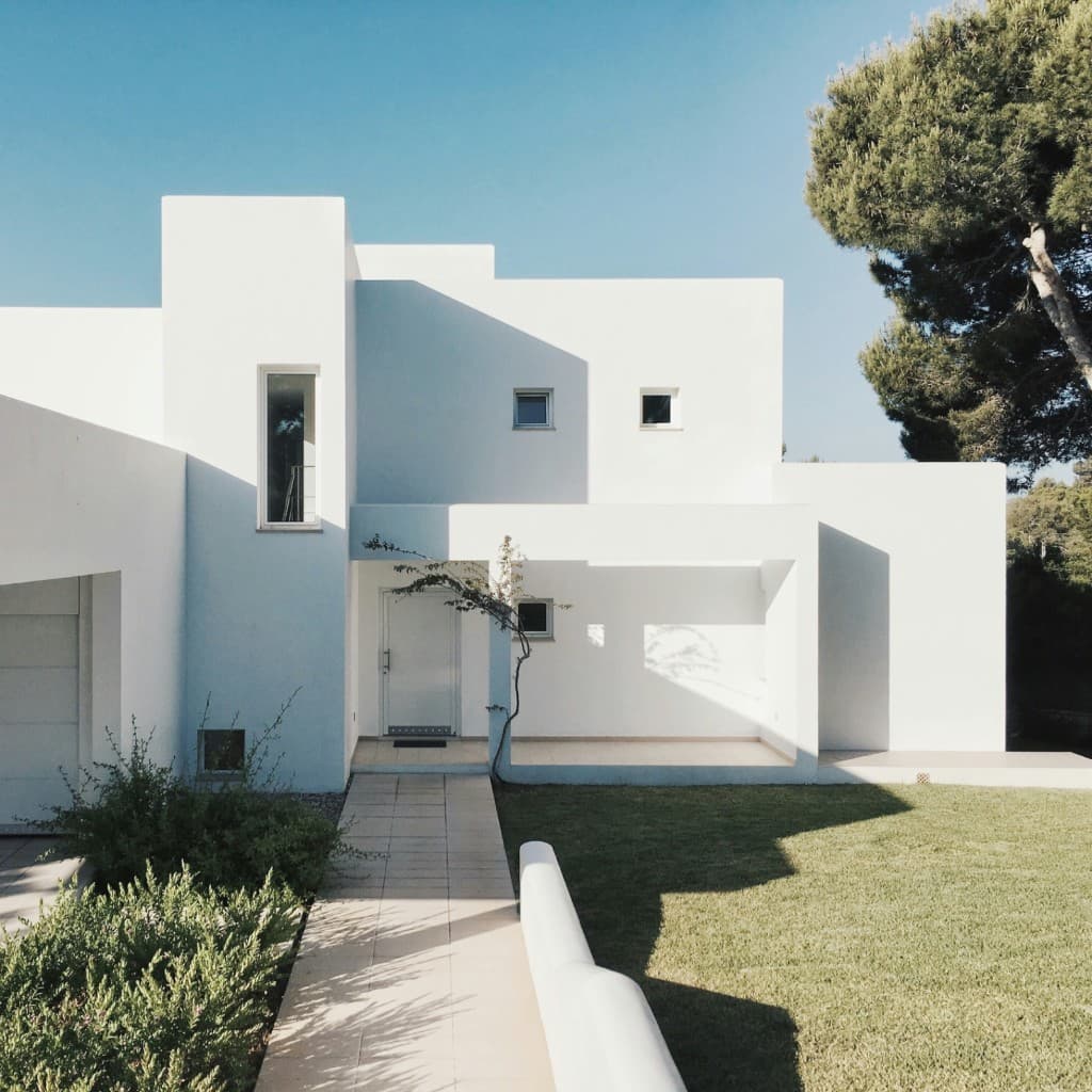 Modern white villa with clean geometric lines, green lawn, and blue sky